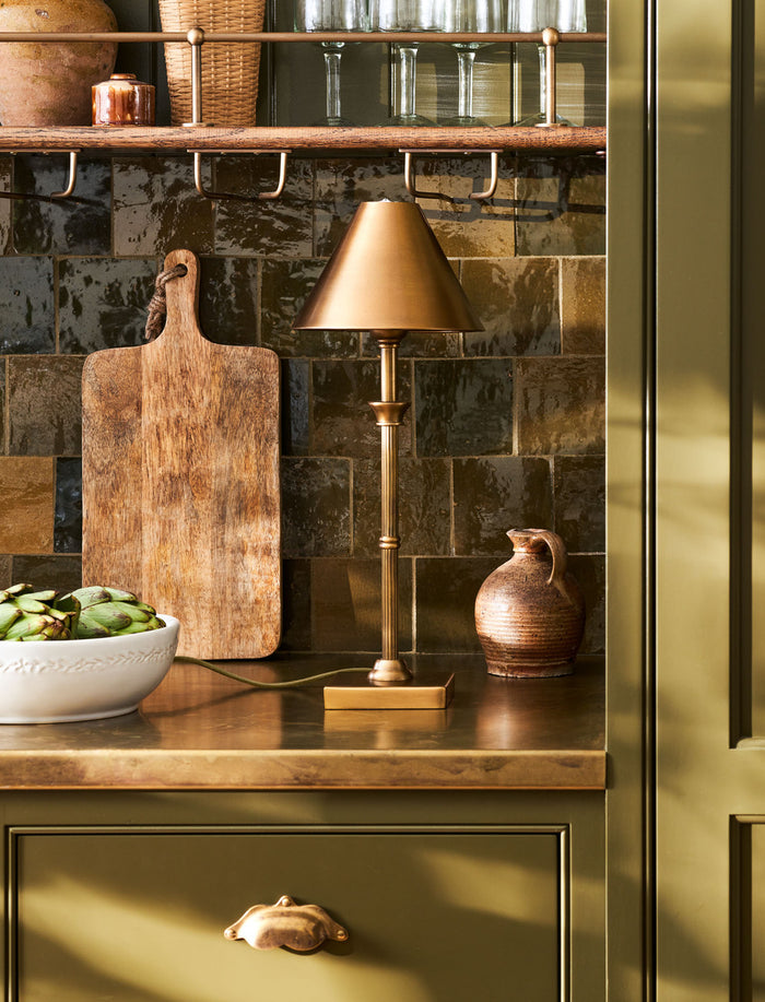 Kelmscot table lamp in antique brass on a plain background