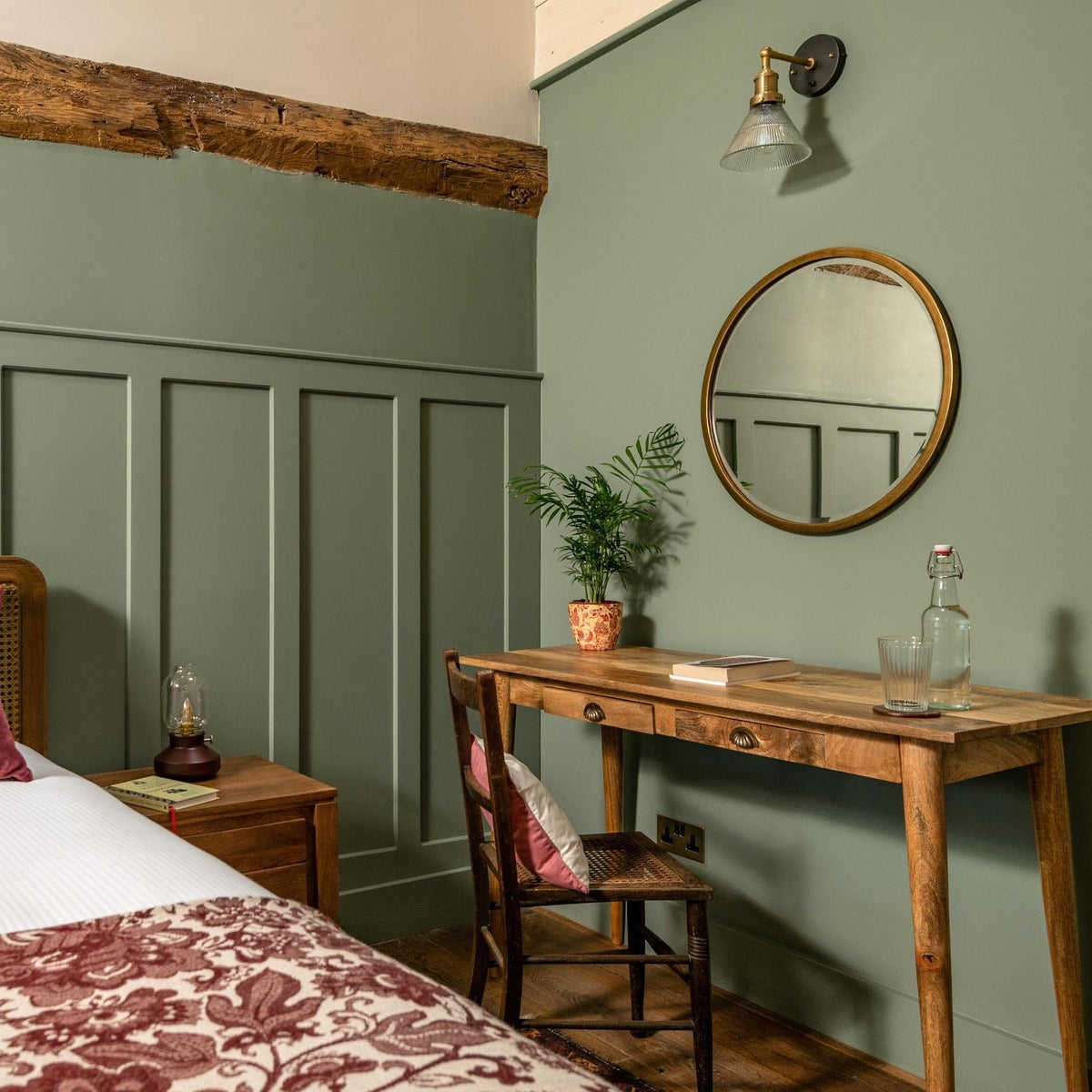 Brass funnel wall light above a bedside table
