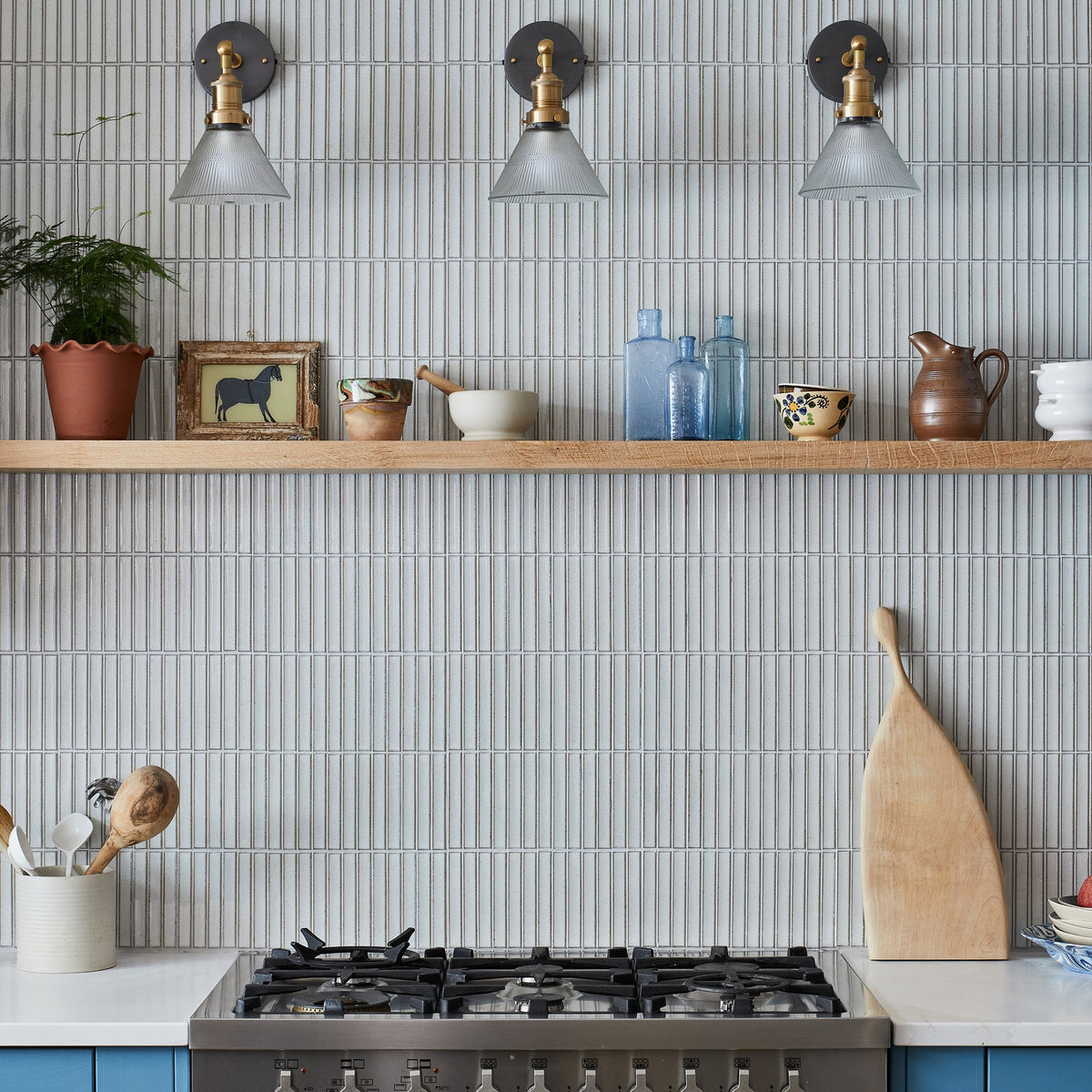 Glass funnel wall light mounted in a blue kitchen