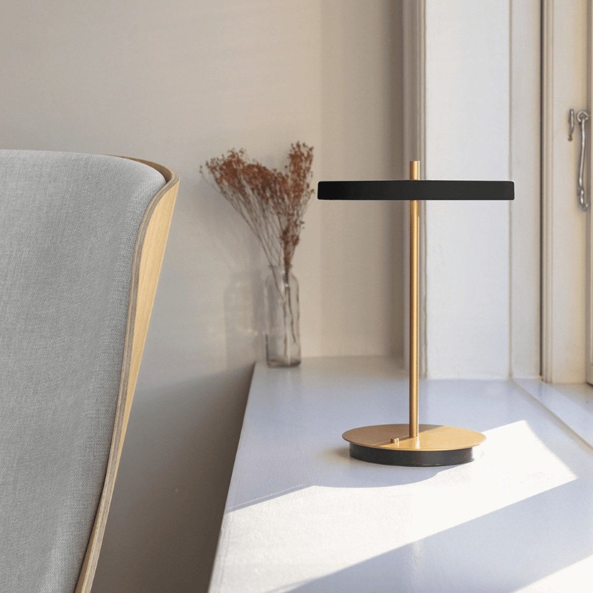 Asteria Move lamp beside a reading chair in oak and grey