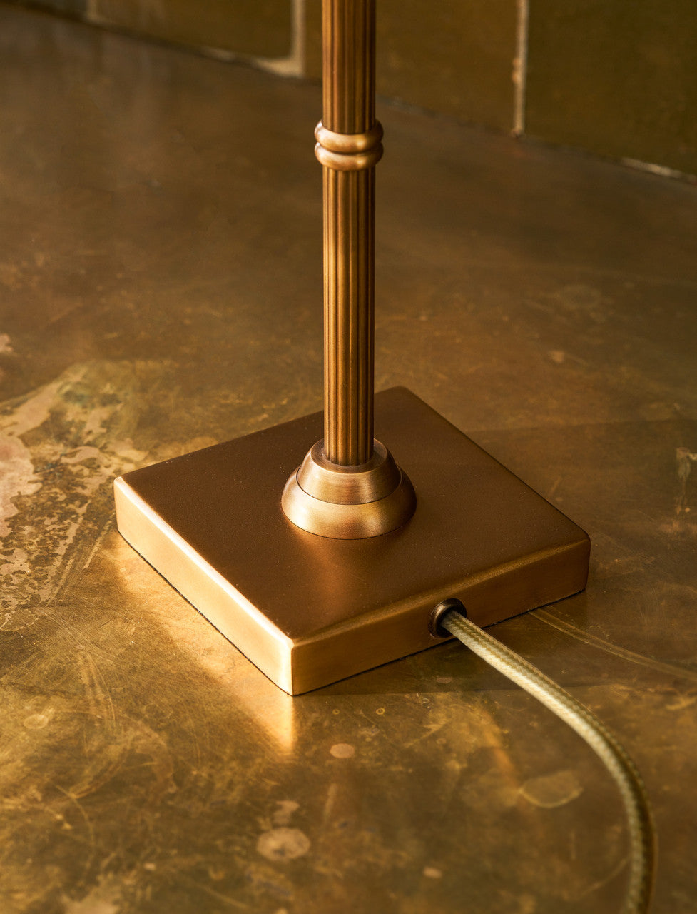 Kelmscot table lamp shown lit, highlighting its iron shade