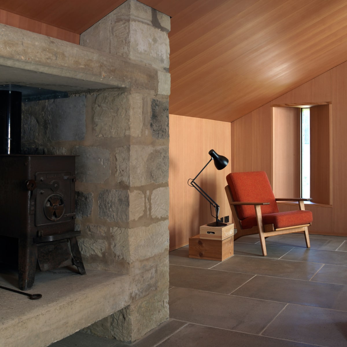 Type 75 desk lamp in black styled beside an armchair in a stone-walled living room